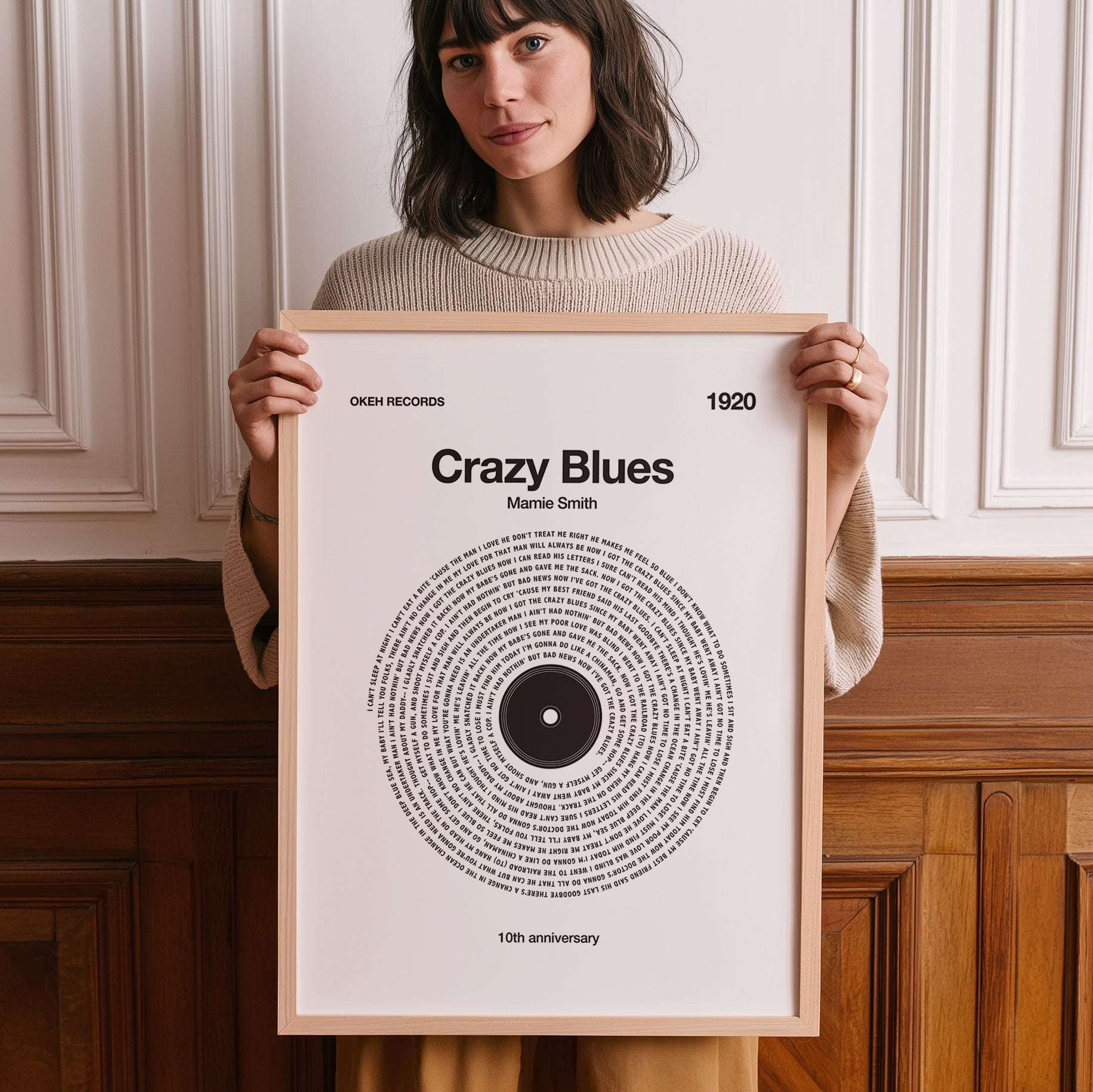 Woman holding a framed poster of 'Crazy Blues' by Marvin Smith with a decorative wall in the background.