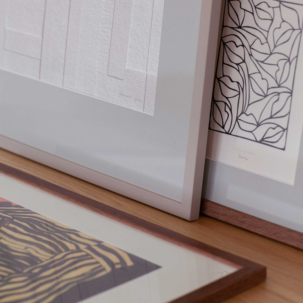 a wooden surface with three framed artworks displayed on it. The artworks include abstract designs and patterns, creating a visually appealing and diverse collection.