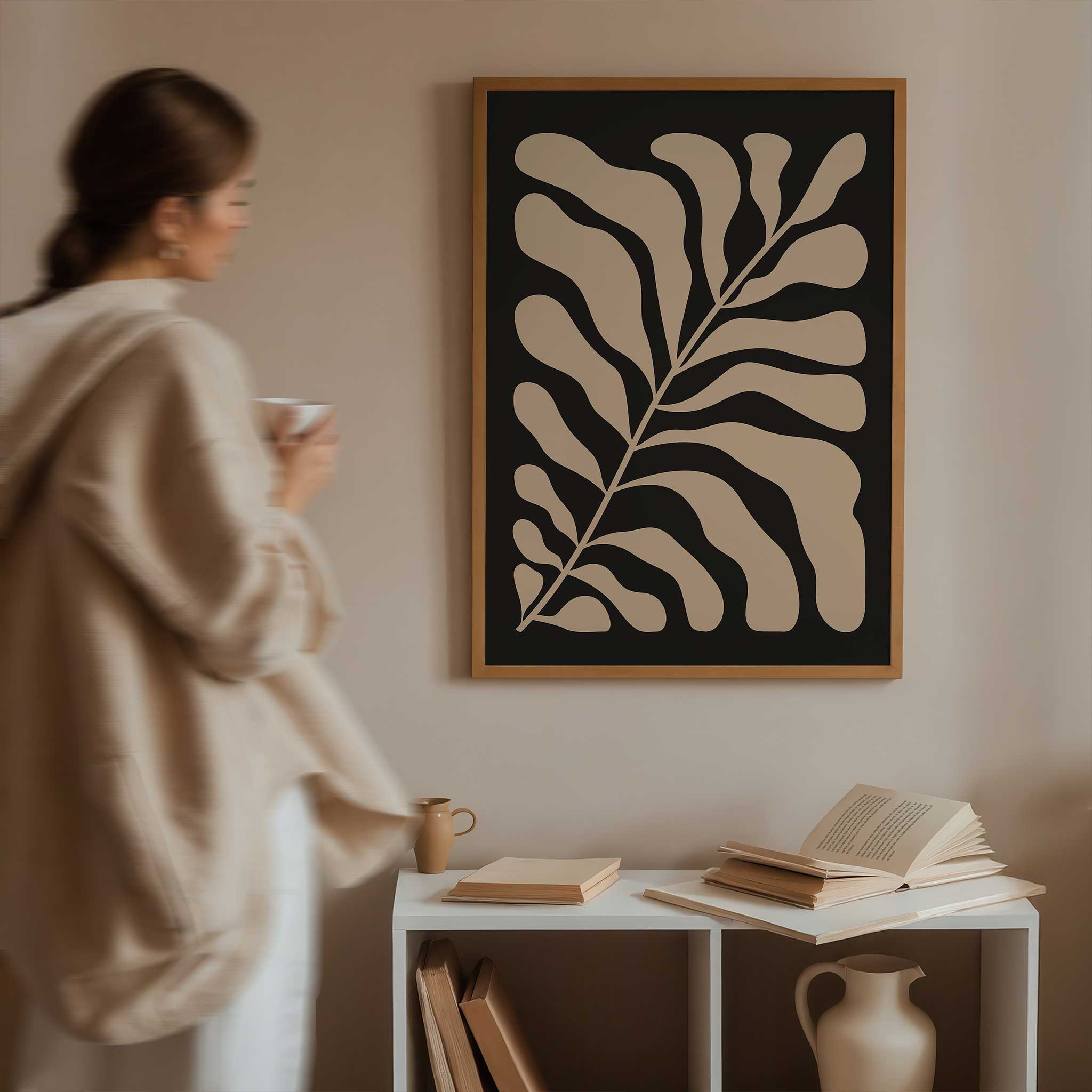 A minimalist print of flowing beige botanical leaves against a solid black background.