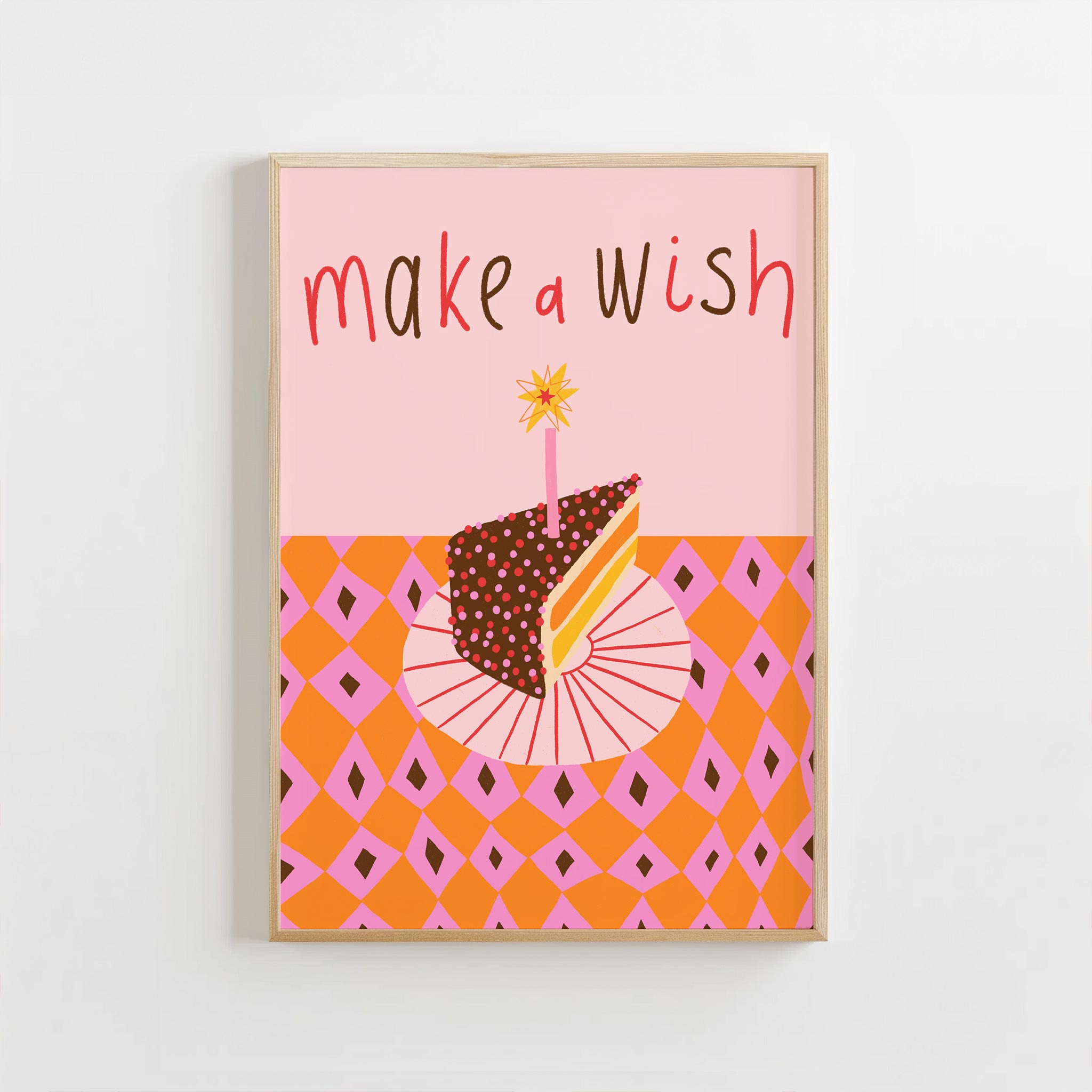 Framed artwork with a cake illustration and 'make a wish' text on a pink and orange background.