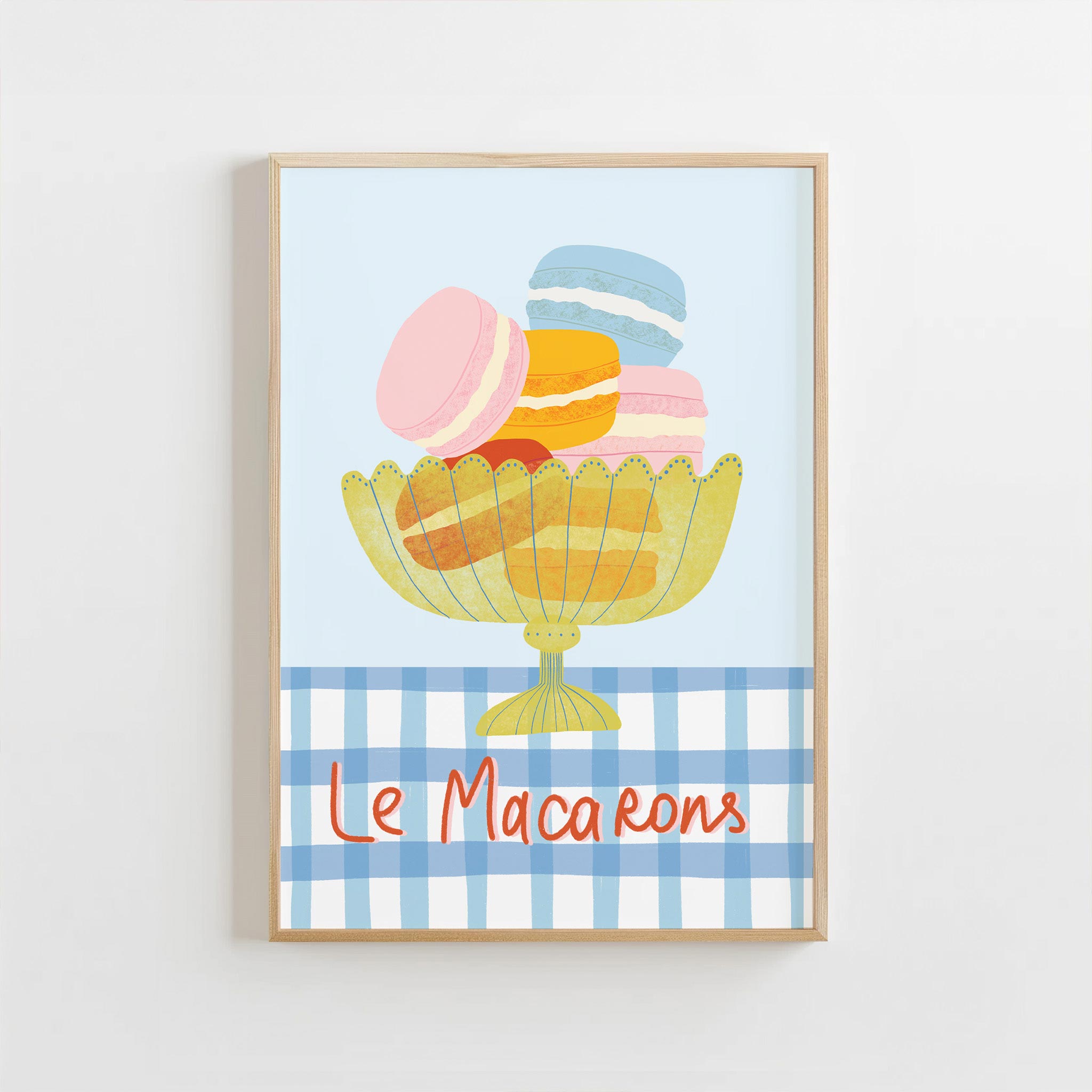Framed artwork of colorful macarons with 'Le Macarons' text on a blue checkered background.