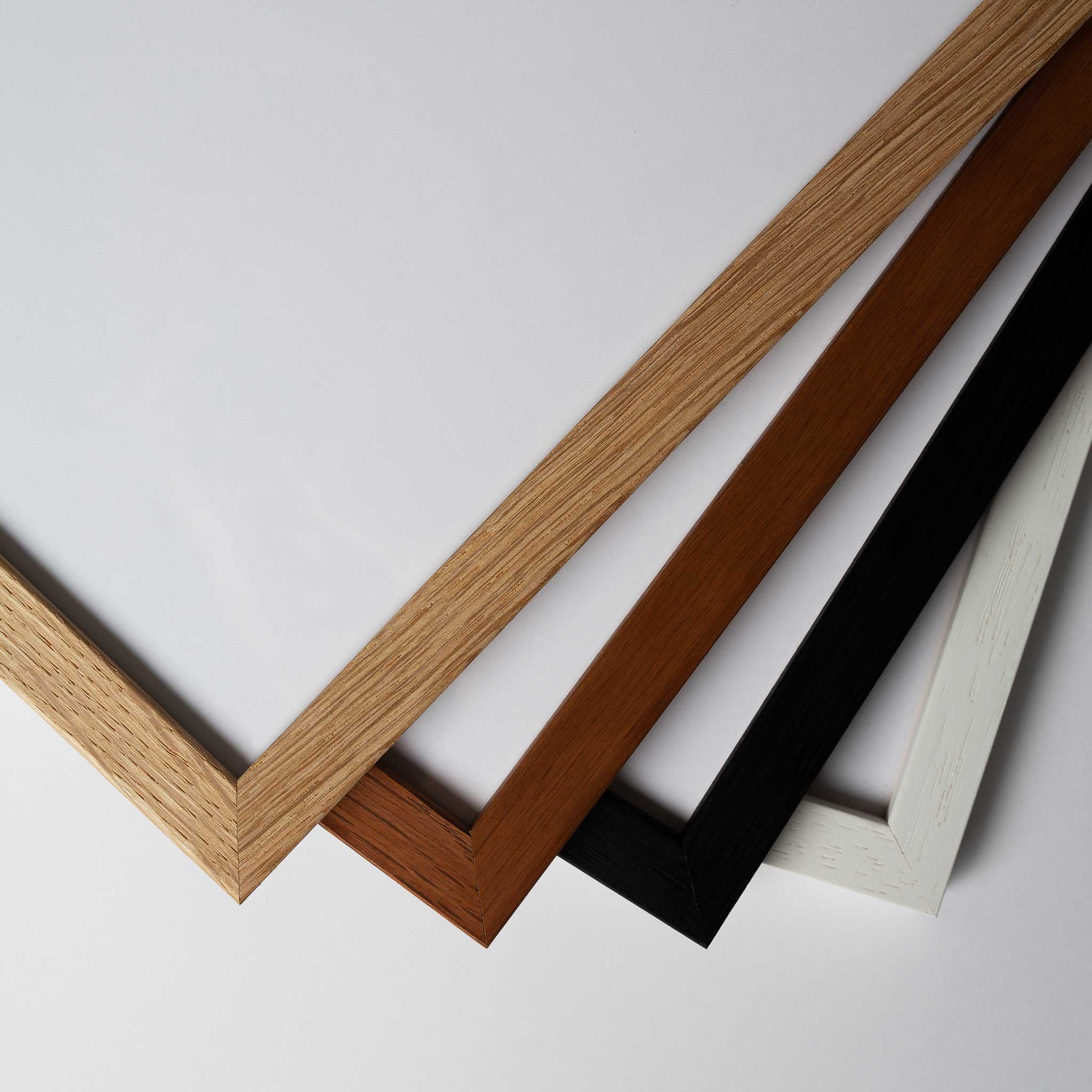 four different colored wooden frames, including light brown, dark brown, black, and white, arranged in a diagonal line.